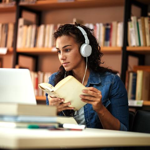 Student studying in the library while wearing headphones